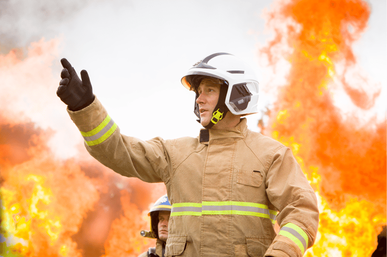 Firefighter standing in front of a large flame.